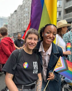 CSD Zwei lächelnde Kolleginnen mit Pride Flagge