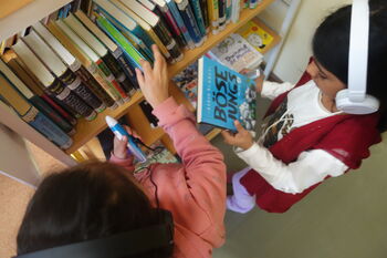 Kinder am Bücherregal mit Kopfhörer